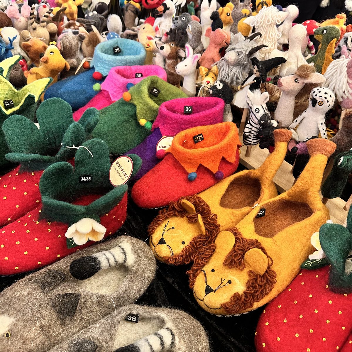 Bunte Filz-Hausschuhe mit Tiermotiven und Filztiere am Stand der Modewelt