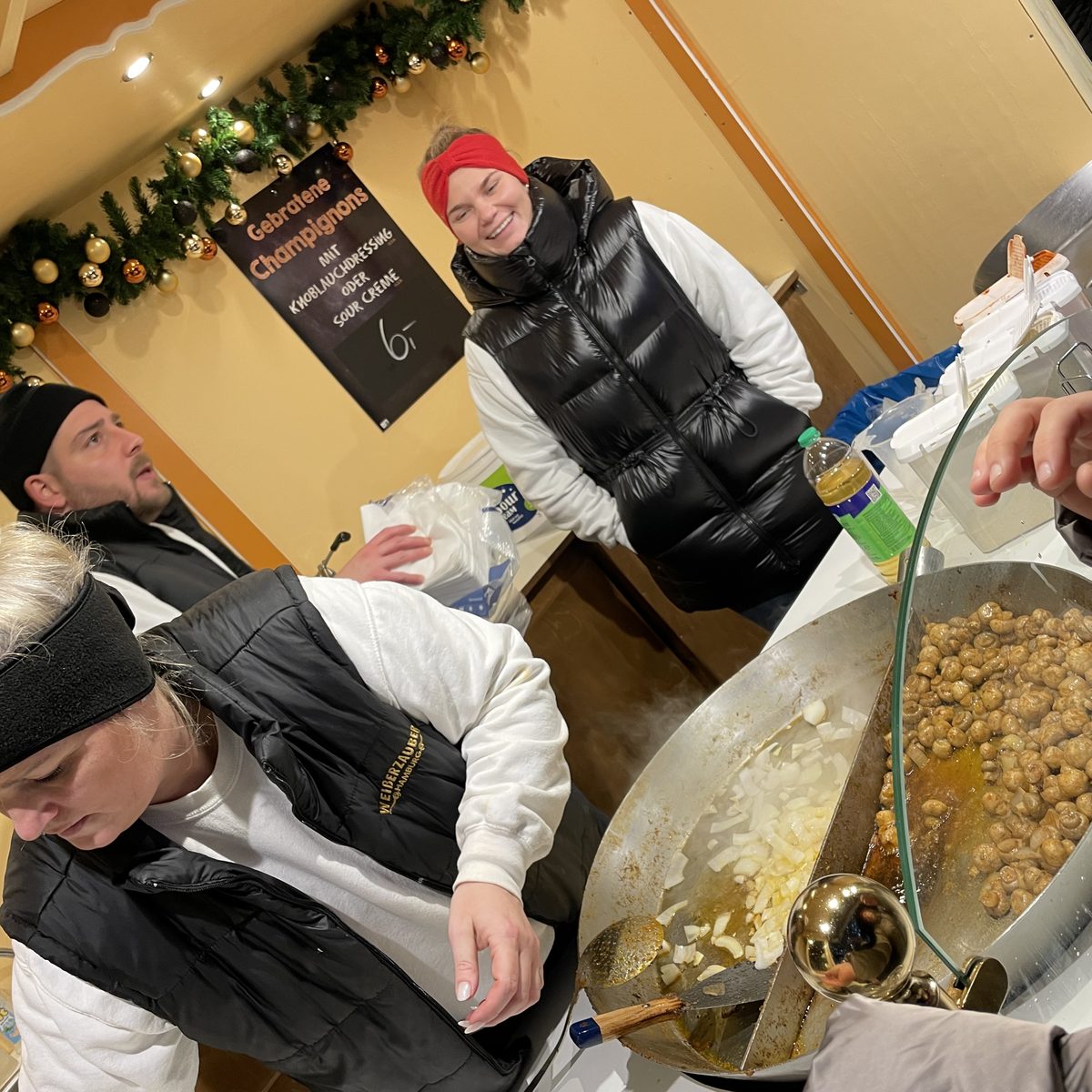 Mitarbeiterinnen und Mitarbeiter braten Champignons am Stand Weiberzauber